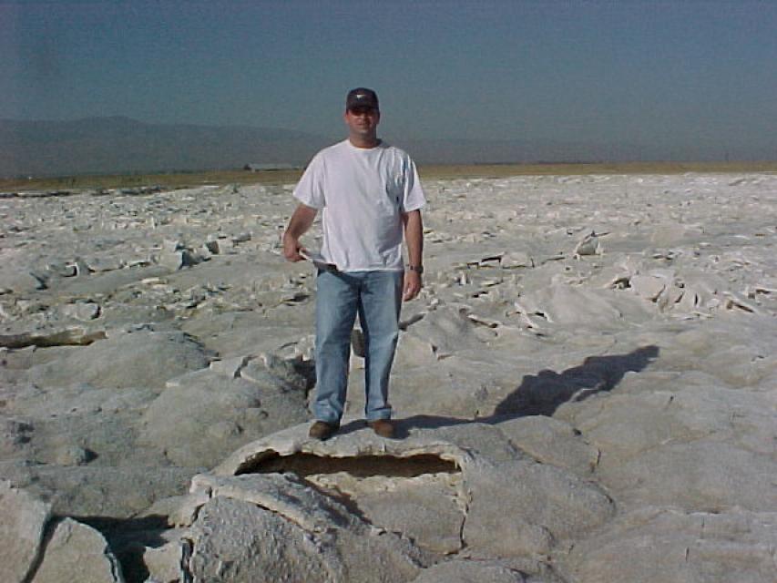 A man stands on an evaporation pond crusted with salt. 