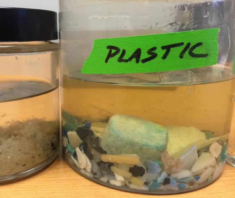 Photo shows bits of plastic at the bottom of a laboratory jar. 